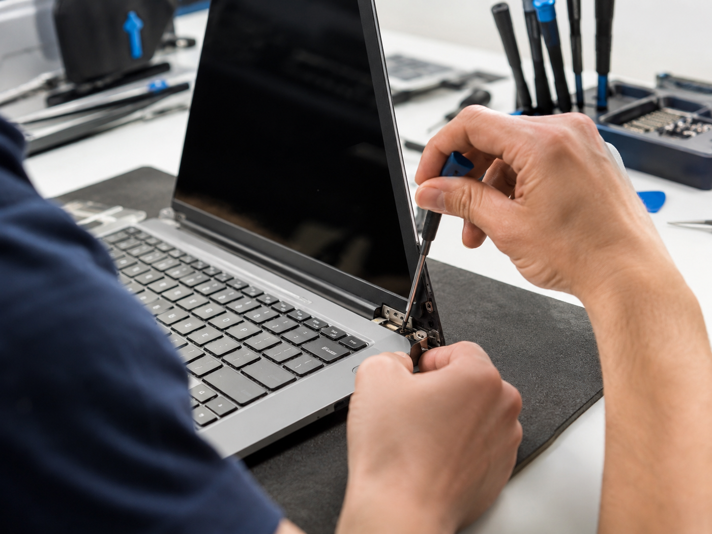 Technician working on laptop hinge and keyboard area